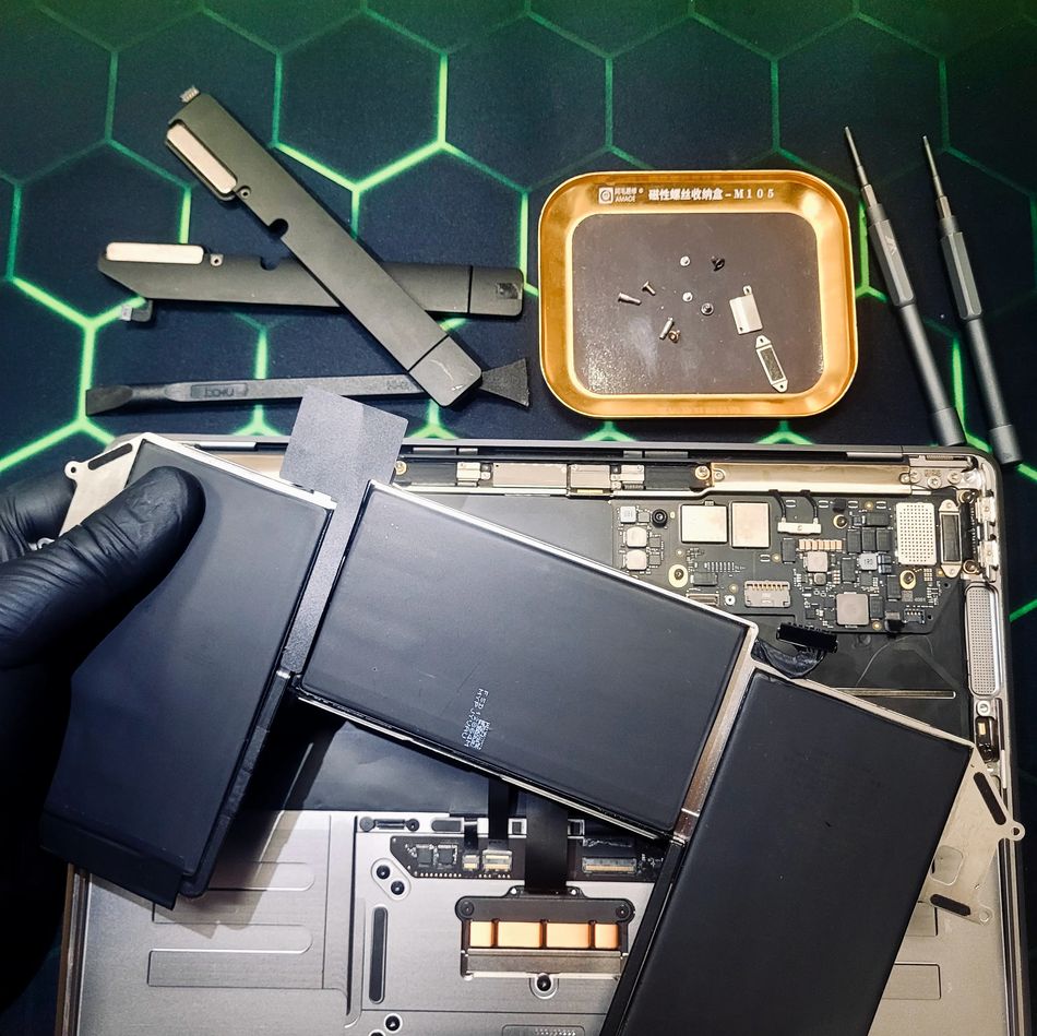 Замена аккумулятора MacBook — извлечение батарейного блока, видна плата и инструменты